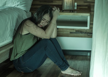 Young Depressed And Sad Asian Korean Woman Sitting On Floor At Bedroom Next To Bed Suffering Depression Problem And Anxiety Crisis Feeling Desperate