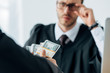 © LIGHTFIELD STUDIOS - selective focus of man holding money near judge in glasses