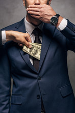 Cropped View Of Man Putting Money In Pocket Of Business Partner Covering Face On Grey