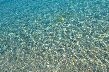 Wall Mural - Beautiful colorful pebbles and big stone under turquoise blue clear water, scenic marine background or texture, top view