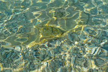 Wall Mural - Beautiful colorful pebbles and big stone under turquoise blue clear water, scenic marine background or texture, top view