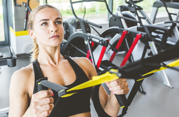 Sticker - Women training with fitness straps in the gym. Beautiful lady exercising her muscles sling or suspension straps.