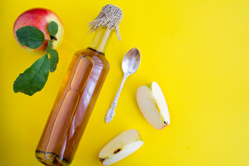 Wall Mural - Apple vinegar cider in the glass bottle on the yellow background.Top view.Copy space.