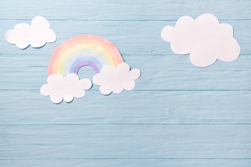 Children or baby background, white clouds with rainbow on the blue wooden background