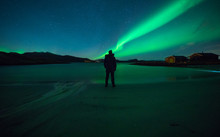 Man Watching Northern Light Dance In Night Sky