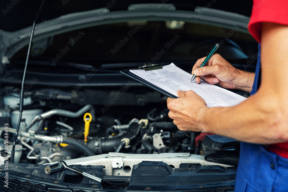 car maintenance and repair - mechanic writing checklist paper on clipboard