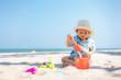© ake1150 - Asian two year old toddler boy playing with beach toys on beach.