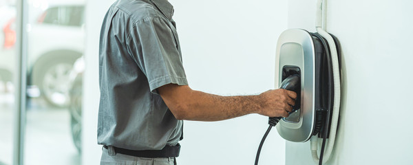 Banner and cover scene of Closeup hand charging the car electrict in maintainance service center which is a part of showroom, economic and technology for safe the world concept