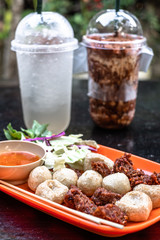 Wall Mural - Thai fried meat balls served with spicy dipping chili sauce and vegetable with drinks in the background. Popular appetizers side dish roasted meat balls. Thai street food.