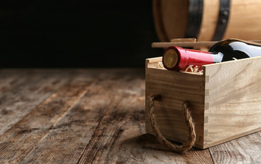 Poster - Crate with bottle of wine on wooden table. Space for text