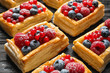 Fresh delicious puff pastry with sweet berries on dark wooden table, closeup