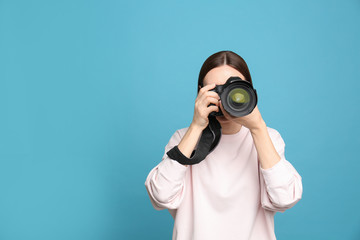 Professional photographer taking picture on light blue background. Space for text