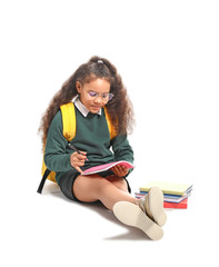 African-American schoolgirl reading book on white background