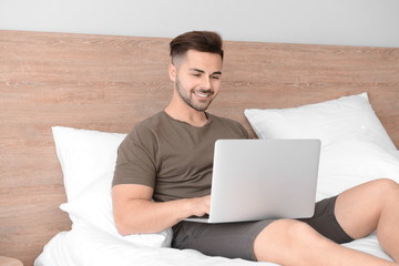 Canvas Print - Handsome man with laptop resting in bedroom