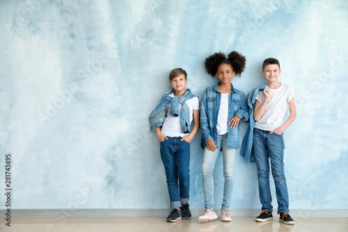 Fotografía Stylish children in jeans clothes near color wall