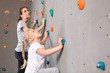 © Pixel-Shot - Young woman with her little daughter climbing wall in gym