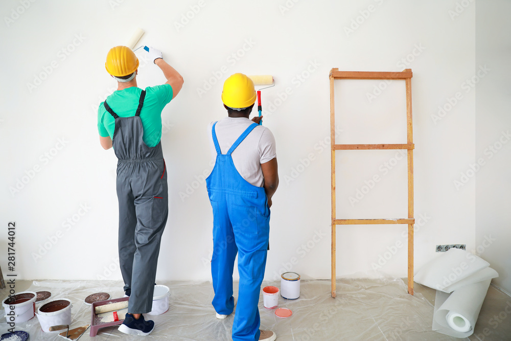 Male decorators painting light wall