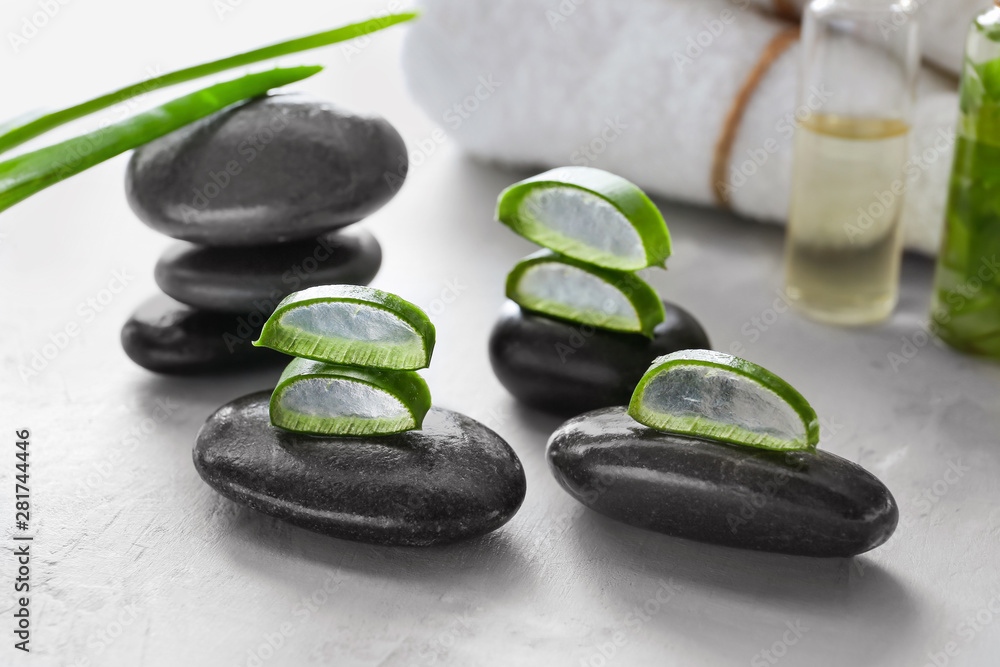 Spa stones with cut aloe vera on light background