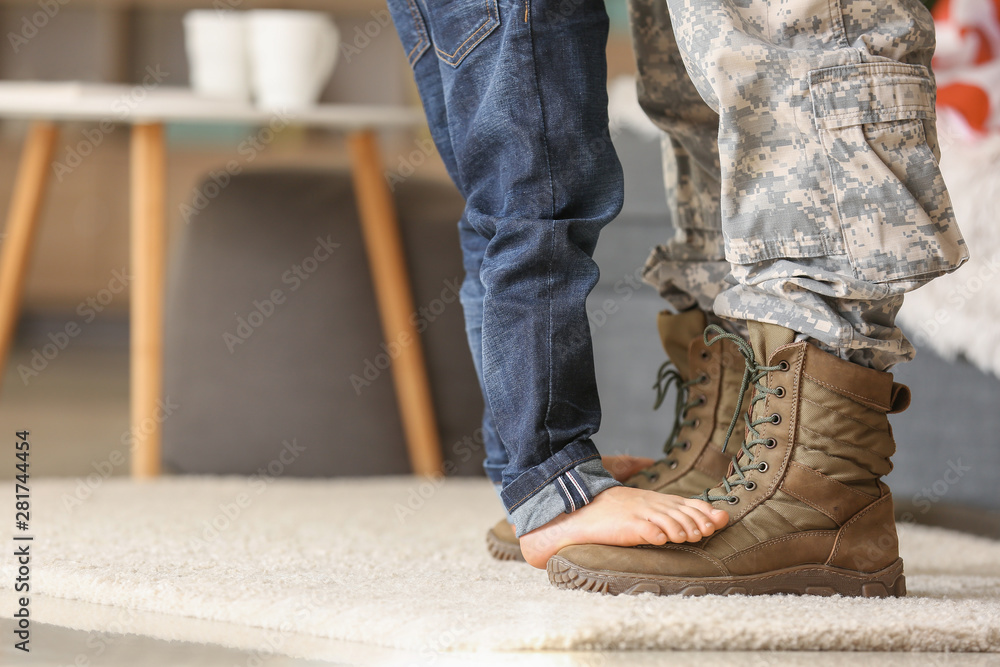 Child standing of feet of his military father at home - obrazy, fototapety, plakaty 