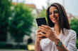 © bnenin - Young cheerful woman using smart phone, focus on hands.