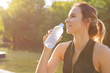 © fotofabrika - Young beautiful woman drinking water during morning jogging in the park