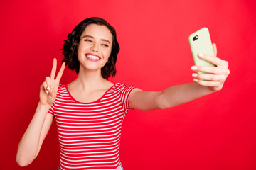 Wall Mural - Portrait of her she nice-looking attractive lovely winsome cheerful cheery friendly wavy-haired girl taking making selfie showing v-sign isolated over bright vivid shine red background