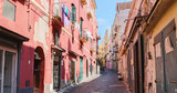 Fototapeta Uliczki - Daylight view on a colorful street of Procida island a sunny summer day. This italian island is famous for its vibrant pastel old houses and the Marina Corricella. Italy (Campania) – Image