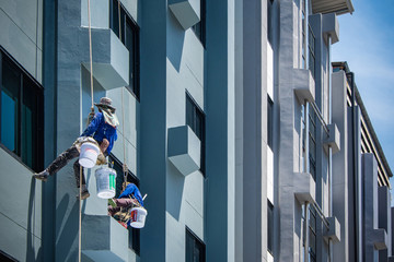 2 painters are hanging on ropes.