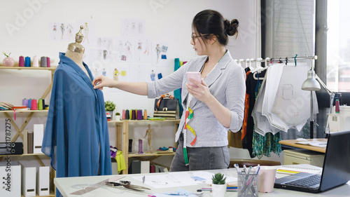 Beautiful Young Dressmaker In Workroom Fixing Dress On