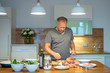 Hobbykoch bereitet zu Hause in der Küche das Essen vor, Süsskartoffel, Fisch Filet, Möhren, grüner Salat, Knoblauch