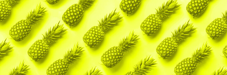 Wall Mural - fresh pineapples on trendy neon yellow color background. top view. pop art design, creative concept.