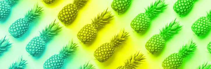 Wall Mural - fresh pineapples on vibrant rainbow gradient background. top view. pop art design, creative concept.