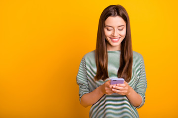 Wall Mural - Photo of excited cheerful girlfriend browsing through her favorite page of some social media while isolated with yellow background