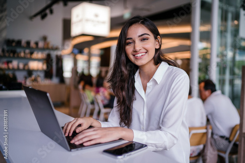 Portrait of a beautiful, young Indian Asian woman working on her laptop in a trendy coworking space Canvas Print