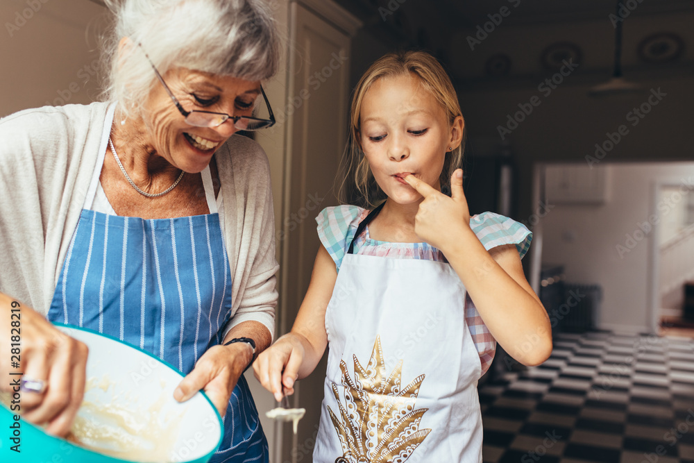 Grandmother and kid having fun making cake in kitchen - obrazy, fototapety, plakaty 