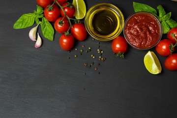 Italian food ingredients for tomato paste: tomatoes, lime, olive oil, Basil, pepper on a black background. Healthy food concept, plant background, natural eco-products, organic food, vegetarian, veg