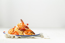 Spaghetti With Pan Seared Prawns, Oven Roasted Tomatoes And Parmesan, On An Enamel Plate With A Fork And Linen. Light Background.