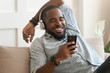 © fizkes - Smiling young african man wearing headphones listen to mobile music