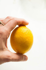 Yellow lemon on woman's hand on the white backround