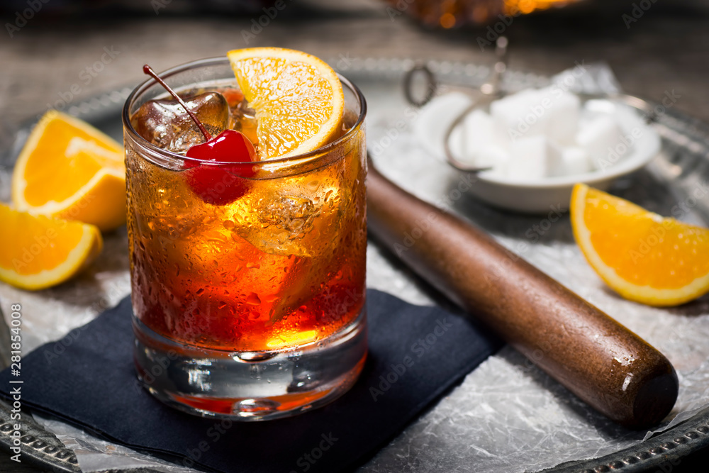 Old Fashioned Cocktail On Ice with Cherry and Orange Garnish, Sugar Cubes, and Muddler on Tray - obrazy, fototapety, plakaty 