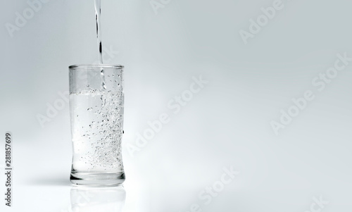 Fotomural pour water into the glass on a white background