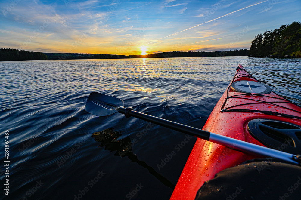 red plastic kayak on calm water in the sunset - obrazy, fototapety, plakaty 