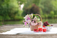 A Picnic In The Summer.Wicker Basket With A Bouquet Of Peony Flowers ,fruit Wine And Strawberries And Bunches Of Grapes