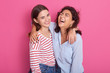 © sementsova321 - Close up portrait of happy lesbian girls hugging each other, have satisfied expessions, being in high spirit, wearing casual shirts isolated on pink background. Same sex love and relationship concept.
