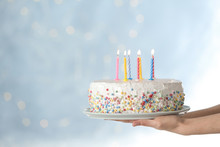 Woman Holding Birthday Cake With Burning Candles Against Blurred Background, Closeup. Space For Text