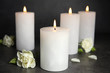 © New Africa - Burning candles and flowers on dark grey table