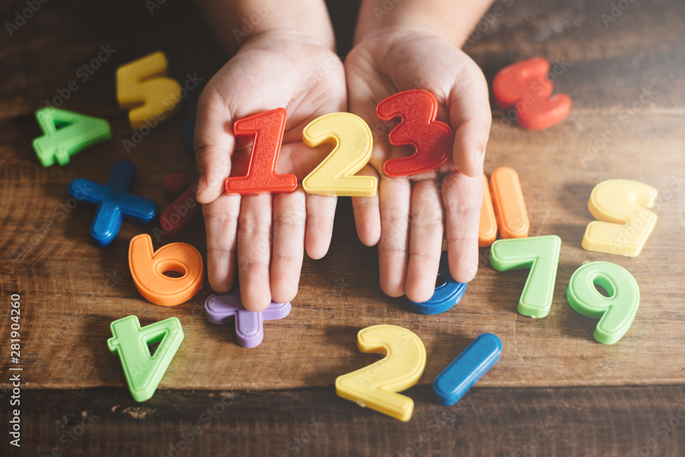 child hands showing a colorful 123 numbers agains wooden table. Concept of Child education, learning mathematics and counting - obrazy, fototapety, plakaty 