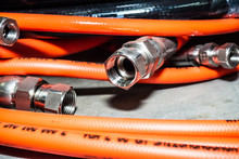 Detail View Of The Connecting Bolt Of The Industrial Flexible Orange Tubes For Water And High Pressure Gas On A Metal Shelf