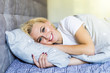 © dianagrytsku - Good morning. Attractive young woman smiling and looking at camera while lying in the bed at home
