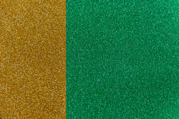 Wall Mural - Golden and green sparkling background from small sequins, closeup. Brilliant shiny backdrop from textile. Shimmer paper